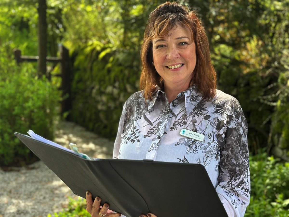 Independent civil celebrant Jane Young holding a ceremony folder outside a West Sussex venue